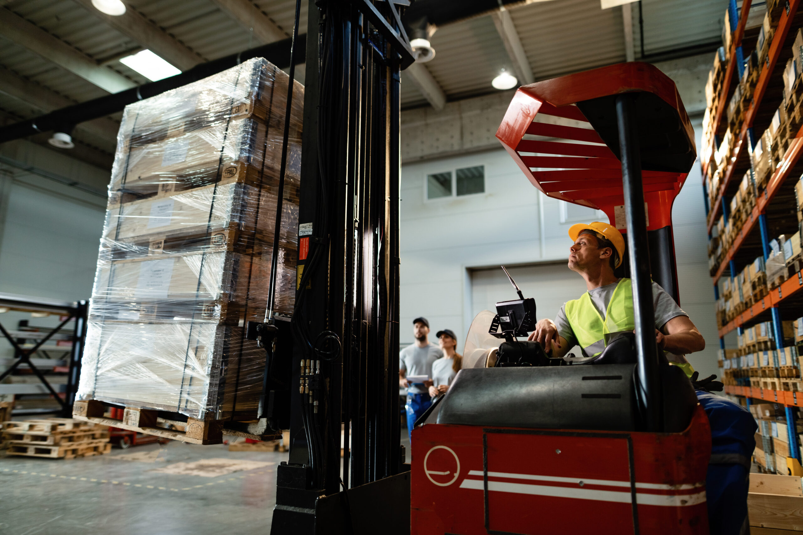 forklift-operator-loading-cargo-while-working-warehouse-his-colleagues-are-background-scaled.jpg